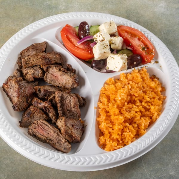 A divided plate with grilled steak, a Greek salad, and orange rice.