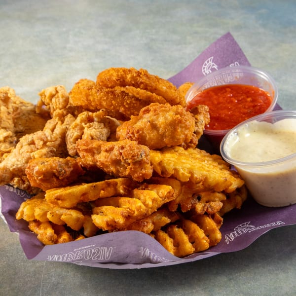 Crispy fried chicken tenders and waffle fries with red and white dipping sauces on a purple Ambrosia Pizzeria liner.