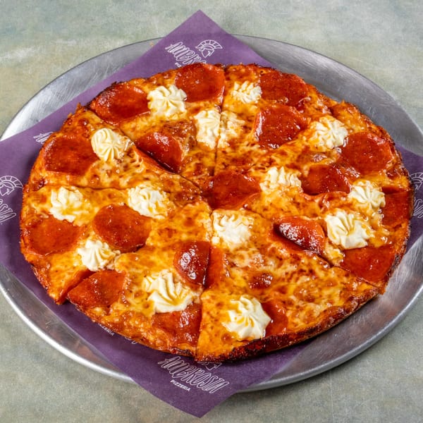 A pepperoni pizza with dollops of white cheese, served on a metal tray with a purple Ambrosia Pizzeria napkin.