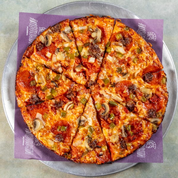 Ambrosia Pizzeria's pepperoni, mushroom, and green pepper pizza, sliced and served on a metal tray.